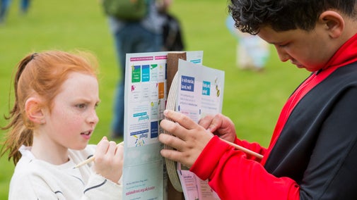 Two children filling out Easter trail activity sheets